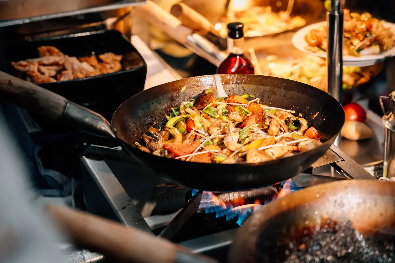 Wok mit Gemüse über offener Flamme an der Live-Cooking-Station